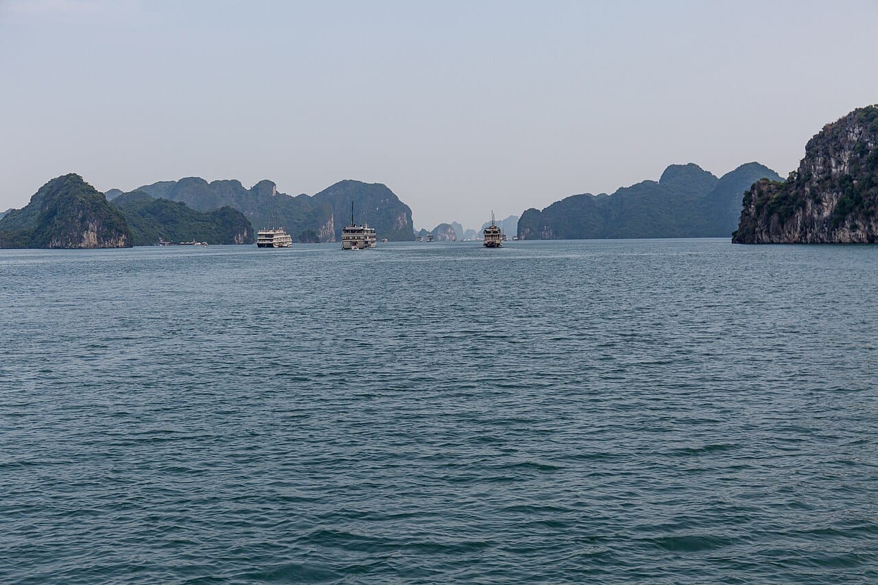 Cruise boats crossing between limestone islands in Ha Long Bay