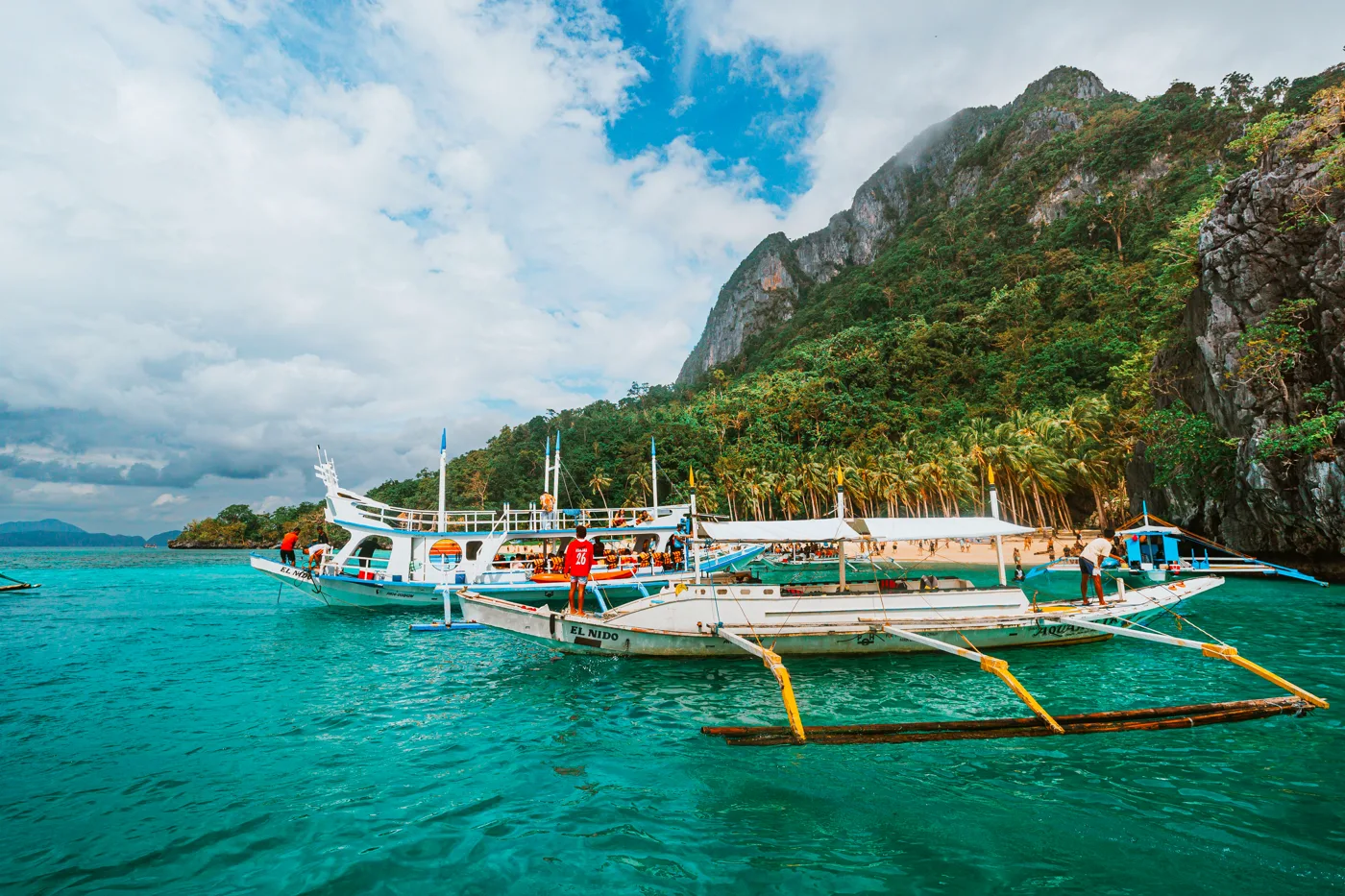 Traditional boats beside limestone cliffs in El Nido, Palawan