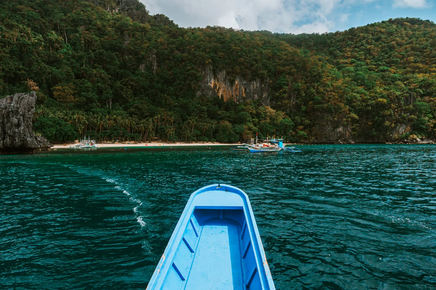View from a blue boat towards the tropical coast of El Nido