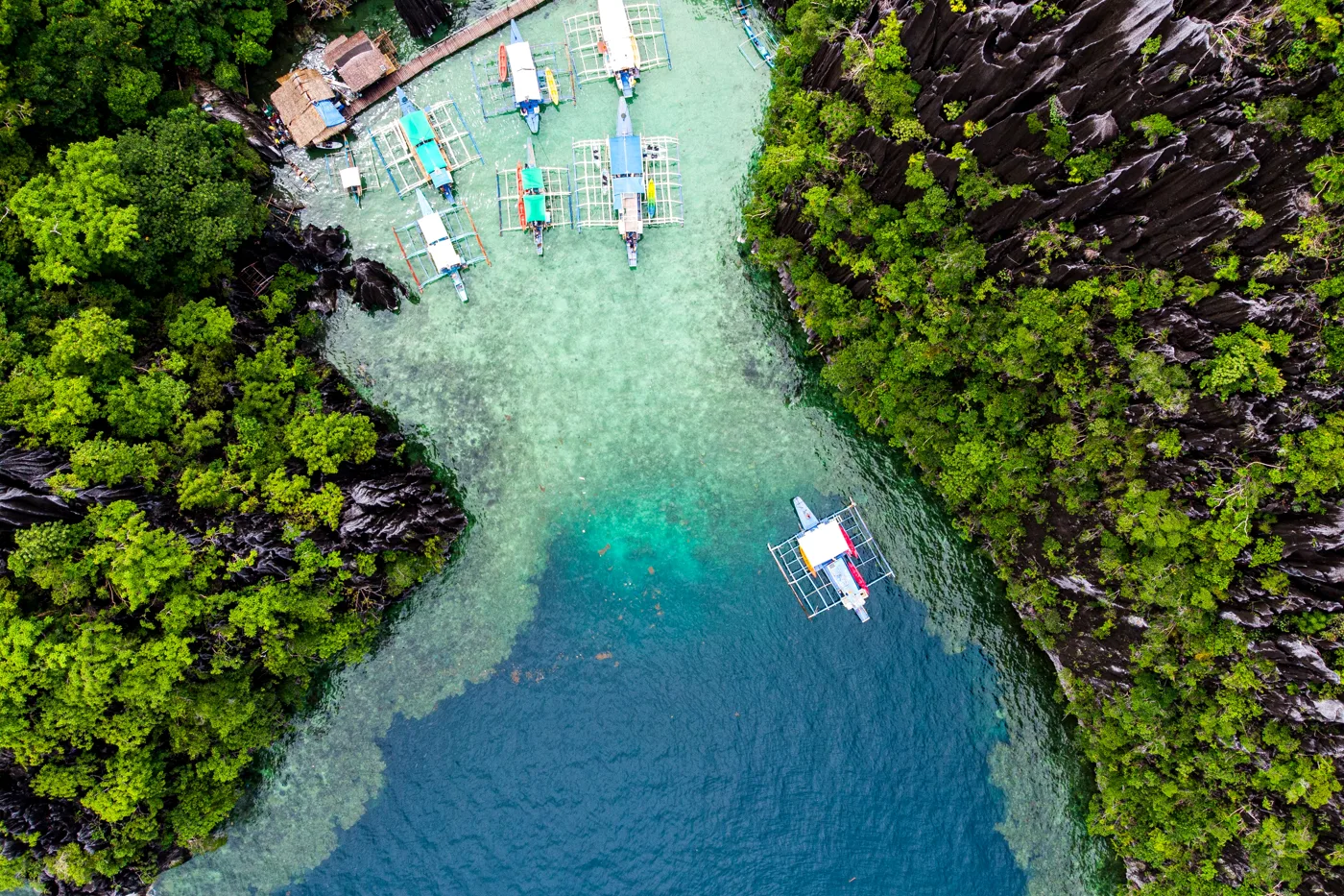 Boats in a turquoise lagoon surrounded by limestone cliffs in El Nido